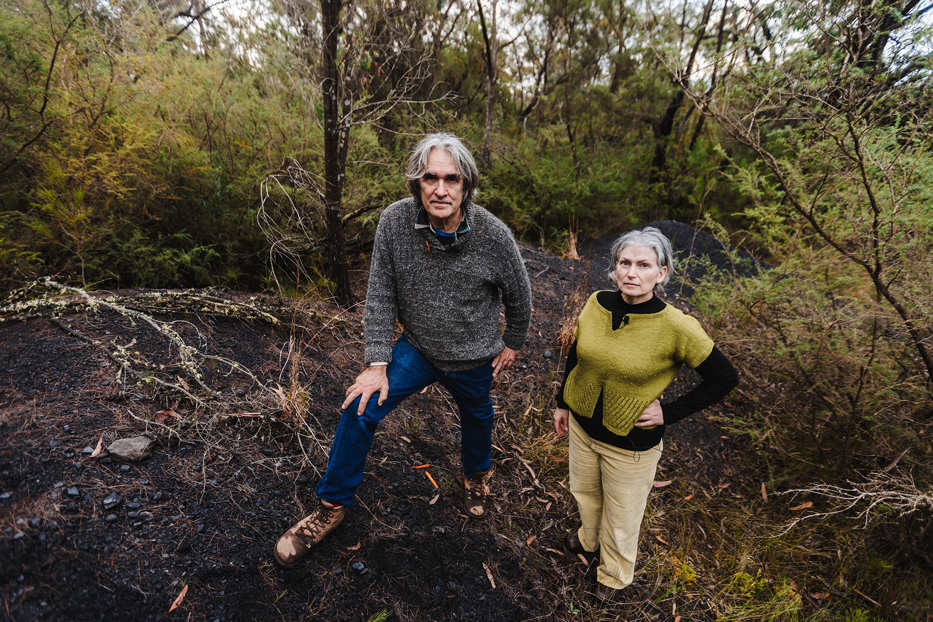 Man and woman stand on coal wash in bushland.